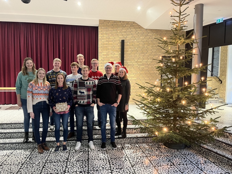 Lehrkräfte und Schüler am Weihnachtsbaum in der Aula